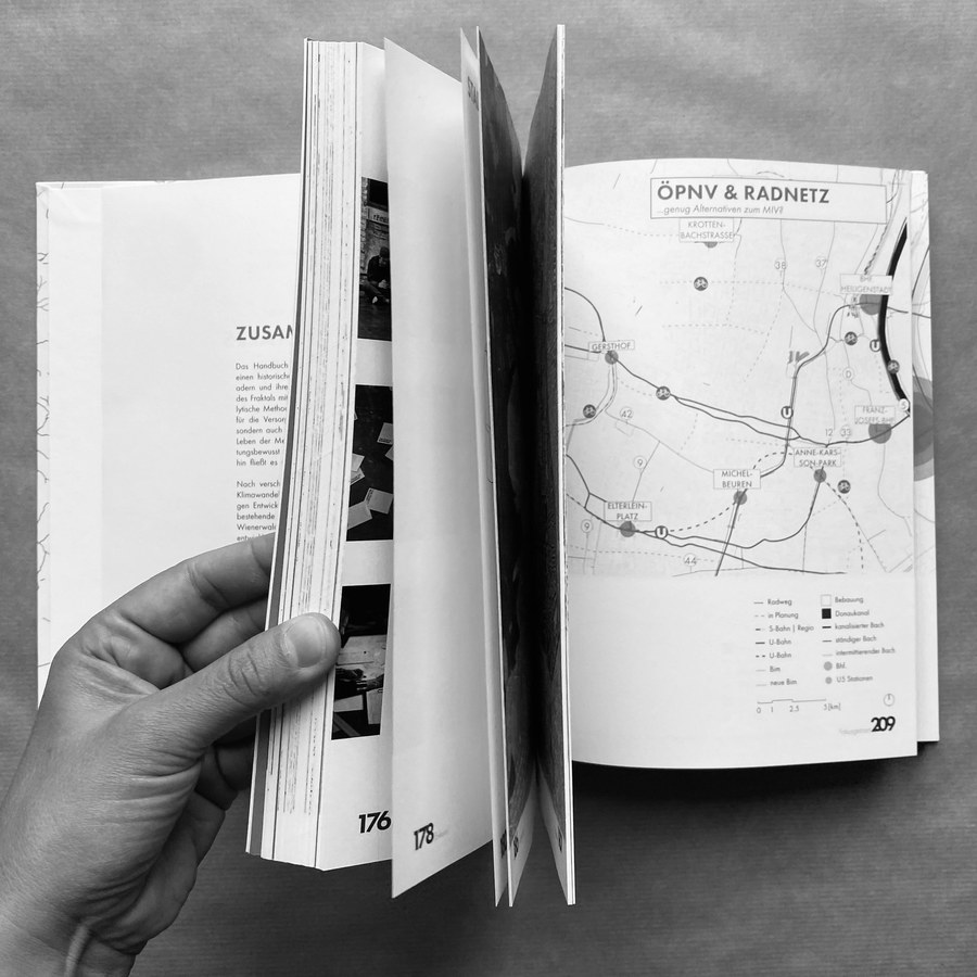 Aufgeschlagenes Handbuch Fraktales Wien mit Karte und Text, in einer Hand gehalten